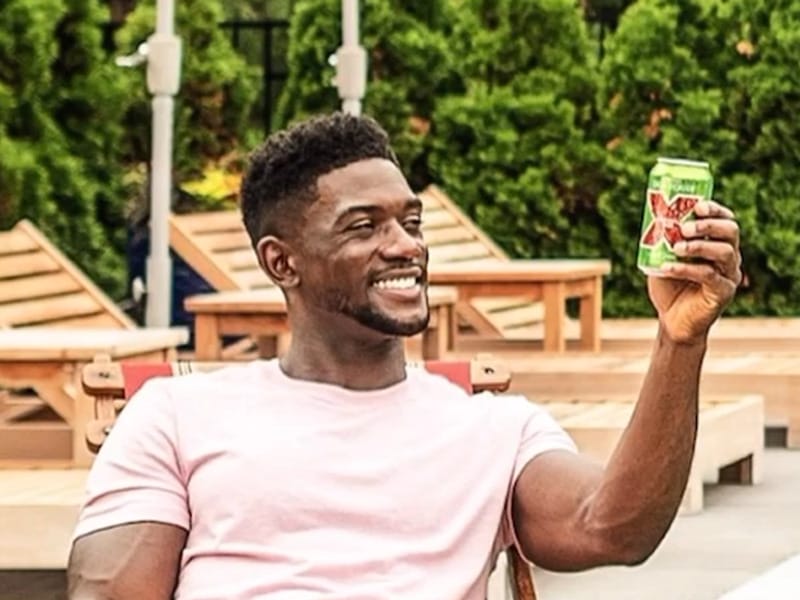 Promotional image of a man raising a can of Dos Equis beer.